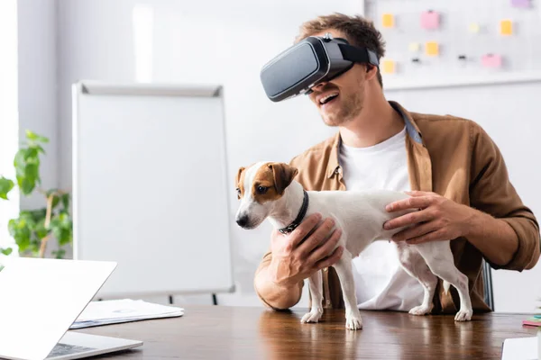 Young businessman in vr headset with jack rassell terrier dog on office desk — Stock Photo