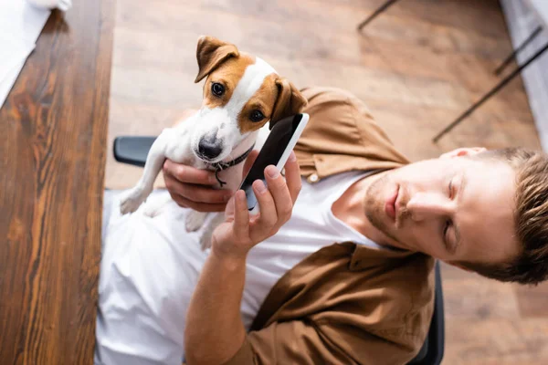 Vista ad alto angolo di uomo d'affari che tiene il cellulare vicino all'orecchio del cane jack russell terrier — Foto stock