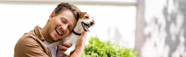 Concepto panorámico del hombre con los ojos cerrados abrazo gato russell terrier perro - foto de stock
