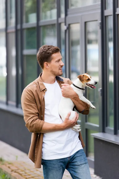 Homem em roupas casuais segurando Jack Russel cão terrier na rua da cidade — Fotografia de Stock