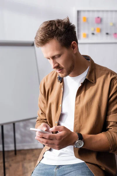 Бизнесмен в повседневной одежде с помощью смартфона во время работы в офисе — стоковое фото