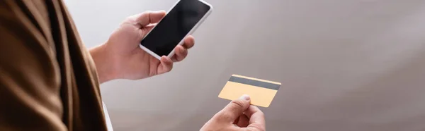 Panoramic shot of businessman holding smartphone and credit card — Stock Photo