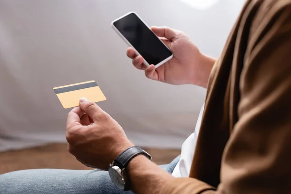 Vista ritagliata di uomo d'affari con smartphone con schermo vuoto e carta di credito — Foto stock