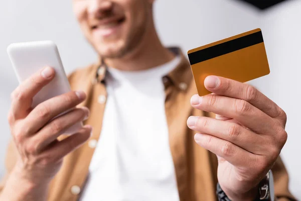 Vista recortada del hombre de negocios con tarjeta de crédito y el uso de teléfono inteligente - foto de stock