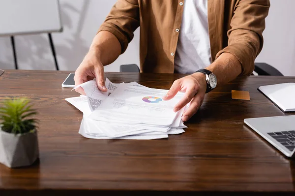 Обрезанный вид бизнесмена, принимающего документы возле гаджетов на столе в офисе — стоковое фото