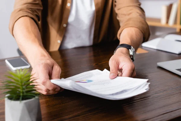 Cropped view of businessman holding documents while working in office — Stock Photo