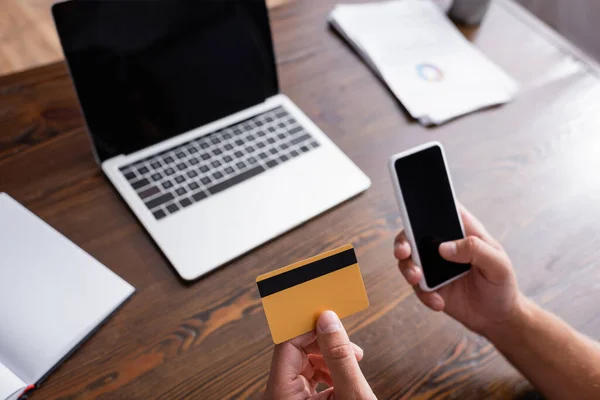 Обрізаний вид бізнесмена, що тримає смартфон з порожнім екраном і кредитною карткою в офісі — стокове фото
