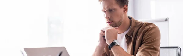 Plan panoramique de jeune homme d'affaires regardant ordinateur portable dans le bureau — Stock Photo