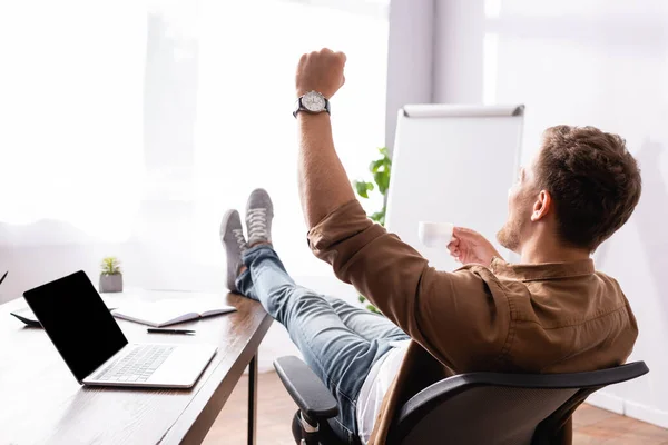 Back view of businessman with cup of coffee showing yeah gesture in office — Stock Photo