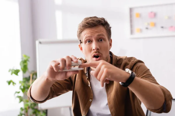 Selective focus of excited businessman holding finger near stapler and looking at camera — Stock Photo