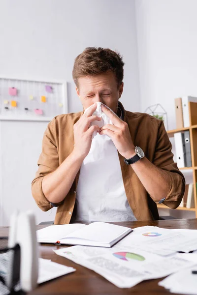 Focus selettivo di uomo d'affari malato che tiene il tovagliolo vicino al naso in ufficio — Foto stock