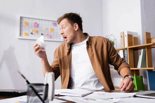 Selective focus of diseased businessman holding napkin while working in office — Stock Photo