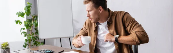 Horizontal crop of sick businessman coughing while holding cup of coffee in office — Stock Photo