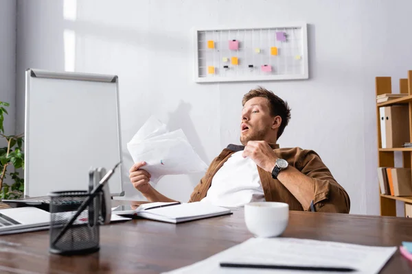 Вибірковий фокус бізнесмена відчуває себе гарячим, тримаючи документи в офісі — стокове фото