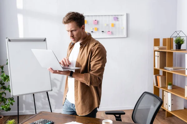 Enfoque selectivo del hombre de negocios en ropa casual usando computadora portátil en la oficina - foto de stock