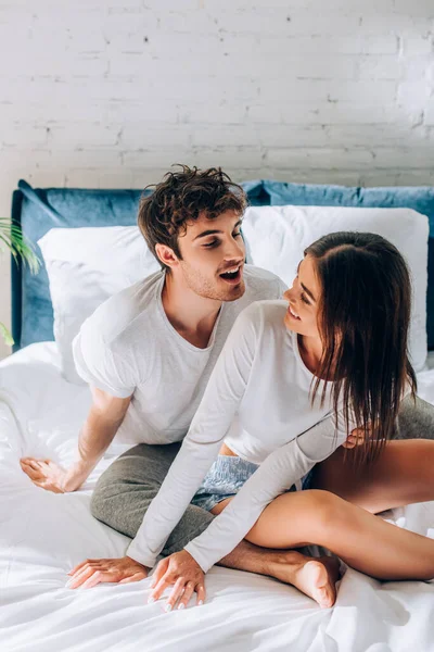 Jovem casal sentado na cama e olhando uns para os outros — Fotografia de Stock