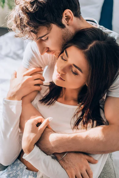 Young woman sitting and touching boyfriend with closed eyes — Stock Photo