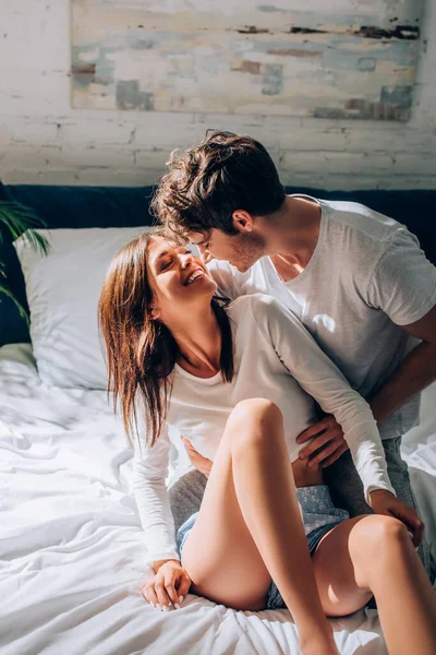 Радостный мужчина обнимает и смотрит на девушку в постели — стоковое фото