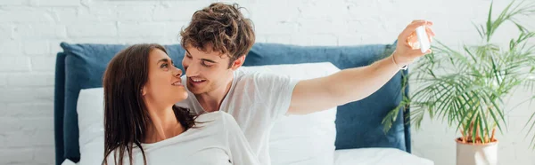 Panoramic shot of young couple taking selfie and looking at each other — Stock Photo