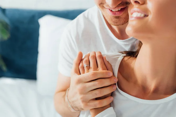 Cropped view of man embracing girlfriend with engagement ring on finger in bedroom — Stock Photo