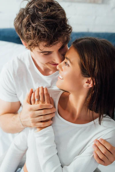 Man embracing girlfriend with engagement ring in bedroom — Stock Photo