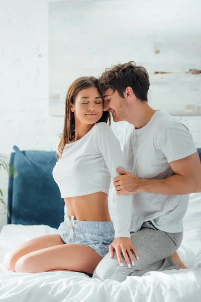 Woman in pajamas touching boyfriend on bed at morning — Stock Photo