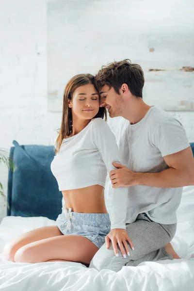 Femme en pyjama touchant petit ami sur le lit le matin — Photo de stock