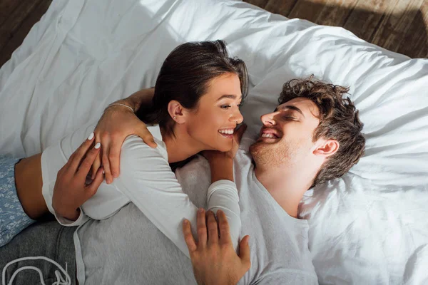 Vista de ángulo alto de pareja joven abrazándose y mirándose en la cama - foto de stock