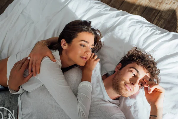 Vista de ángulo alto de la pareja en pijama acostado en la cama por la mañana - foto de stock