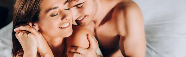 Horizontal image of shirtless man touching shoulder of girlfriend on bed — Stock Photo