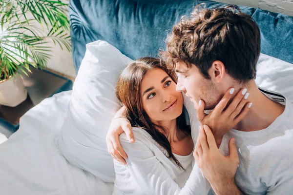 Enfoque selectivo de la mujer joven tocando novio en la cama por la mañana - foto de stock