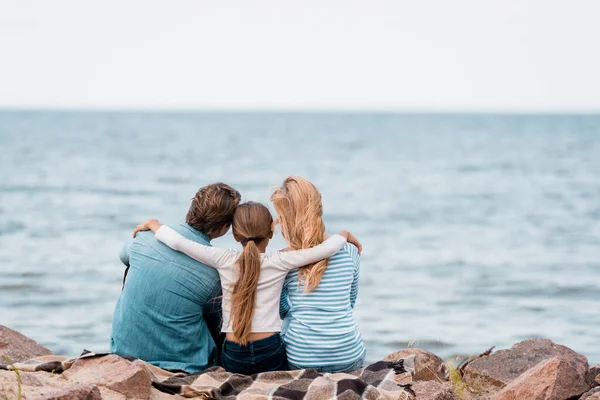Vue arrière de la fille embrassant les parents sur le bord de la mer — Photo de stock