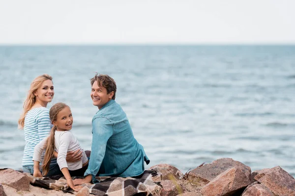 Concentration sélective de la famille avec enfant regardant la caméra sur le bord de la mer — Photo de stock