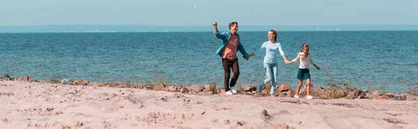 Vue panoramique de la famille avec la fille tenant la main tout en marchant sur la plage — Photo de stock