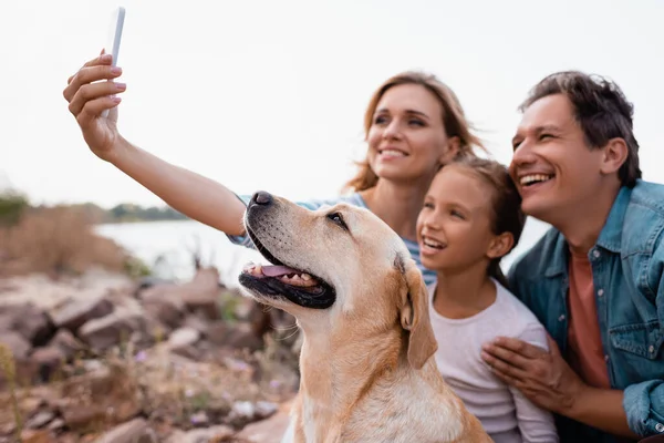 Foco seletivo da família com golden retriever tirando selfie no smartphone na praia — Fotografia de Stock