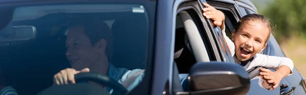 Горизонтальна концепція збудженої дитини, що дивиться крізь вікно автомобіля біля батька — стокове фото