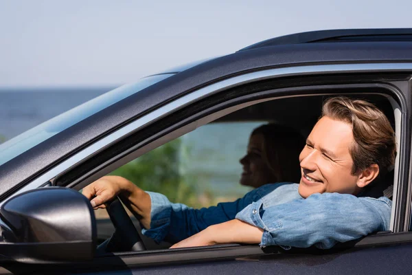 Селективный фокус мужчины, смотрящего в сторону во время вождения автомобиля рядом с женой — стоковое фото