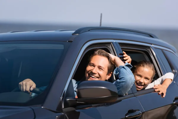 Выборочный фокус отца за рулем автомобиля рядом с взволнованной дочерью — стоковое фото