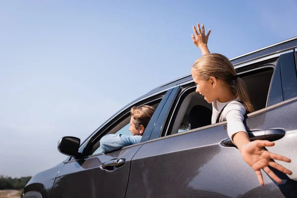 El foco selectivo del chiquitín que mira a través de la ventana del coche cerca del padre - foto de stock