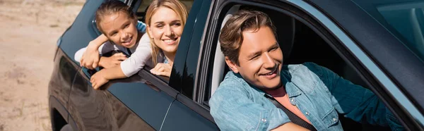 Panoramic concept of man driving car with daughter and wife on back seat — Stock Photo