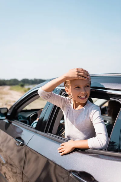 Selektiver Fokus des Kindes mit händenahem Kopf, das im Urlaub mit den Eltern durch das Autofenster schaut — Stockfoto