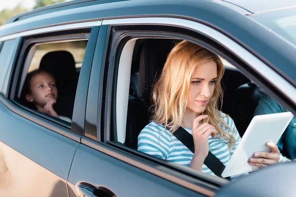Вибірковий фокус жінки за допомогою цифрового планшета під час подорожі з сім'єю в машині — стокове фото