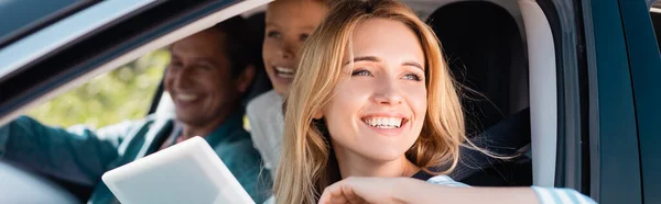 Concetto orizzontale di donna con tablet digitale distogliere lo sguardo mentre si viaggia con la famiglia in auto — Foto stock