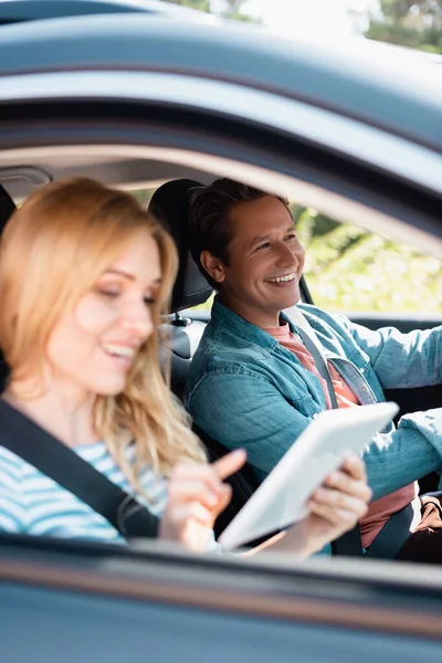 Foco seletivo do homem dirigindo carro perto da esposa usando tablet digital — Fotografia de Stock