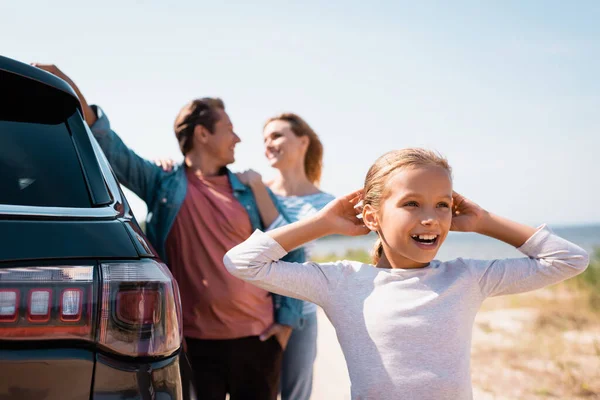 Focus selettivo del bambino guardando lontano vicino ai genitori e auto all'aperto — Foto stock