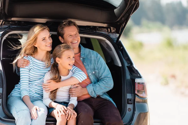 Man embracing wife and daughter in truck of auto — Stock Photo