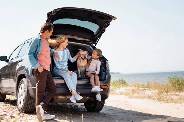 Вибірковий фокус сім'ї з золотим ретривером, що подорожує на машині на пляжі — стокове фото