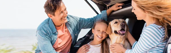 Horizontal crop of family with golden retriever standing near auto on beach — Stock Photo