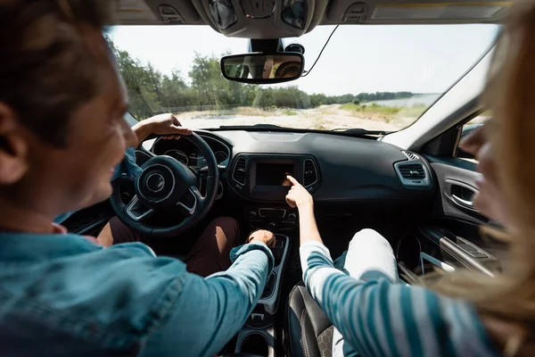 Focus sélectif de la femme pointant du doigt pendant que son mari conduisait une voiture — Photo de stock