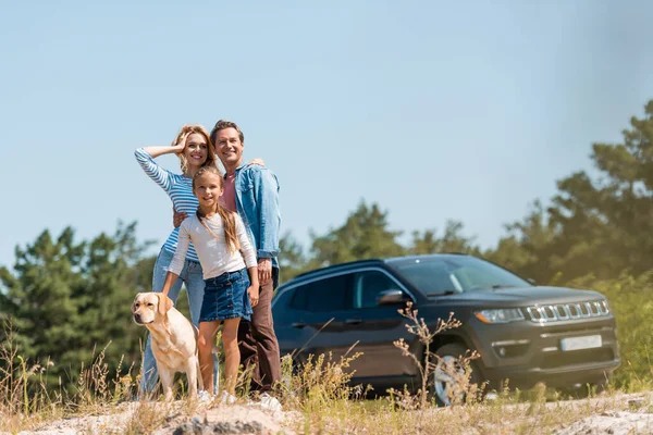 Selective focus of woman embracing husband near child and golden retriever outdoors — Stock Photo